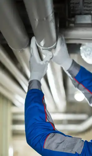 Technician working on overhead pipes Technician inspecting and adjusting overhead metal pipework