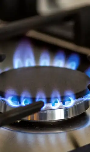 Gas flame on modern cooktop Blue gas flame burning on a stainless steel cooktop