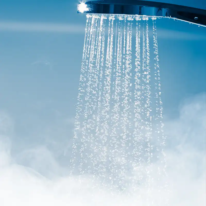 Hot water flowing from a shower head with steam rising, showing reliable hot water system performance