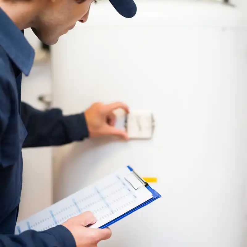 Technician checking hot water system settings Technician adjusting a hot water system control while holding a clipboard