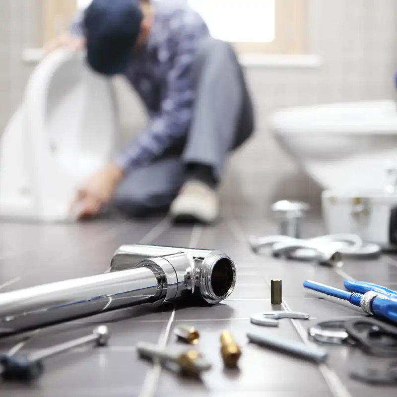 Toilet installation with plumbing tools Plumber installing a toilet with plumbing tools and fittings on the bathroom floor